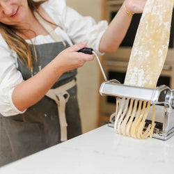 Cooking class woman making pasta using a manual pasta maker.